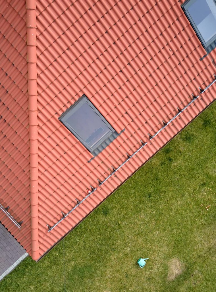 Closeup of attic windows on house roof top covered with ceramic shingles. Tiled covering of building.