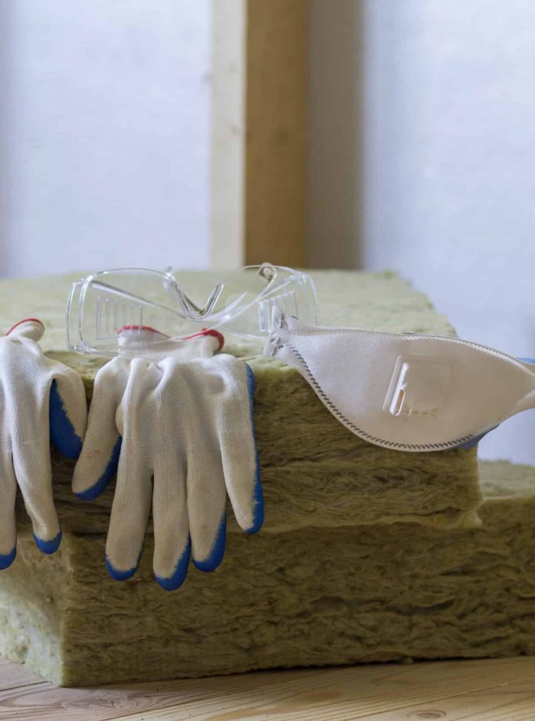 Rock wool and fiberglass insulation staff material for cold barrier. Tools for work with glass wool: protective goggles, glasses and mask. Warm home, economy, construction and renovation concept.